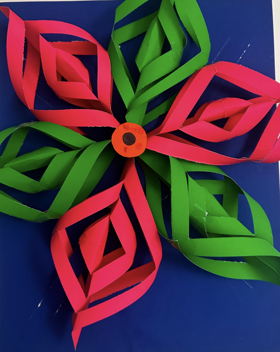 Paper sculpture of a flower made from looped pink and green paper strips around an orange centre, mounted on blue board.