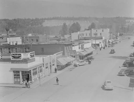 Vintage black and white photo of a small-town main street with old cars